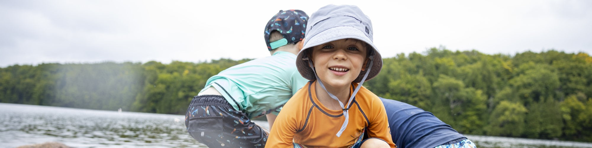 3 enfants d'environ 7 ans en maillots de bain sur une roche dans le lac 